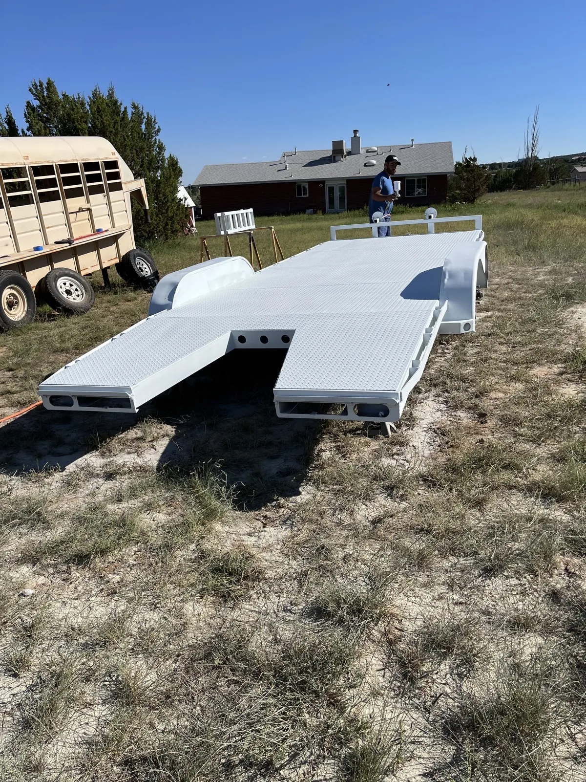 The same car hauler sprayed white, ramps down in the field.