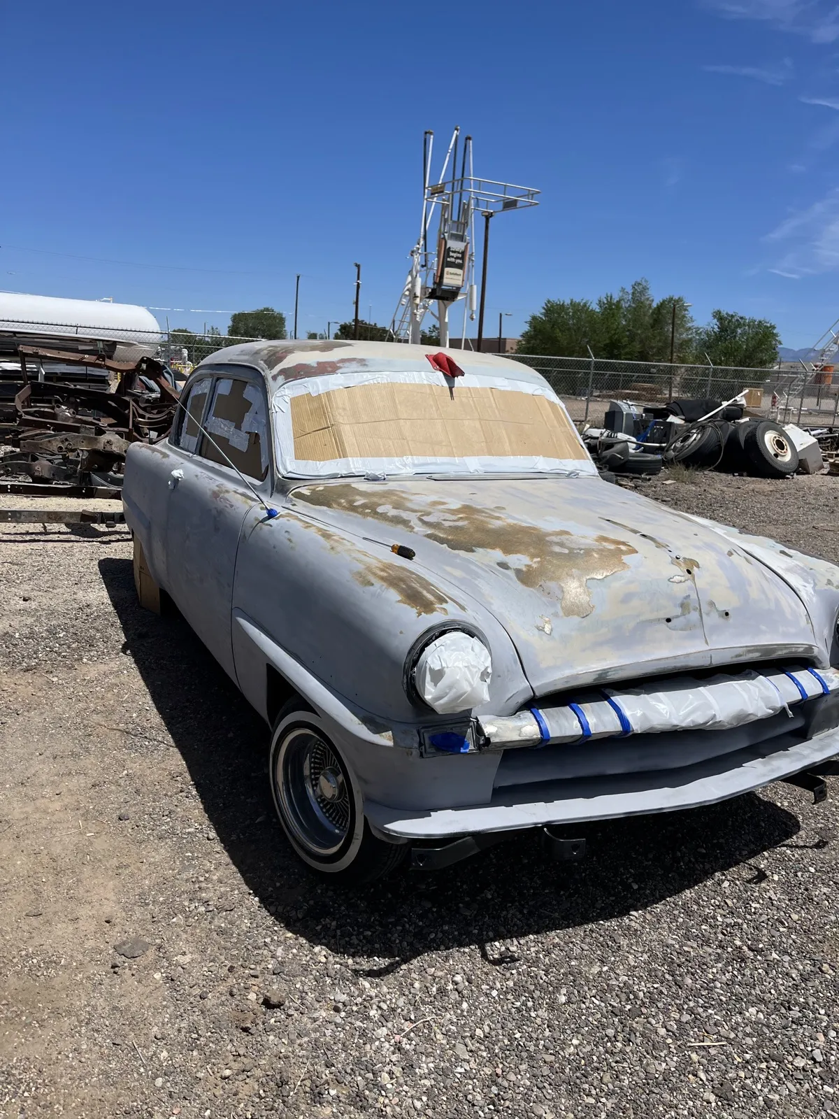 A 1953 Plymouth in worn paint, rust breaking through the hood and roof.